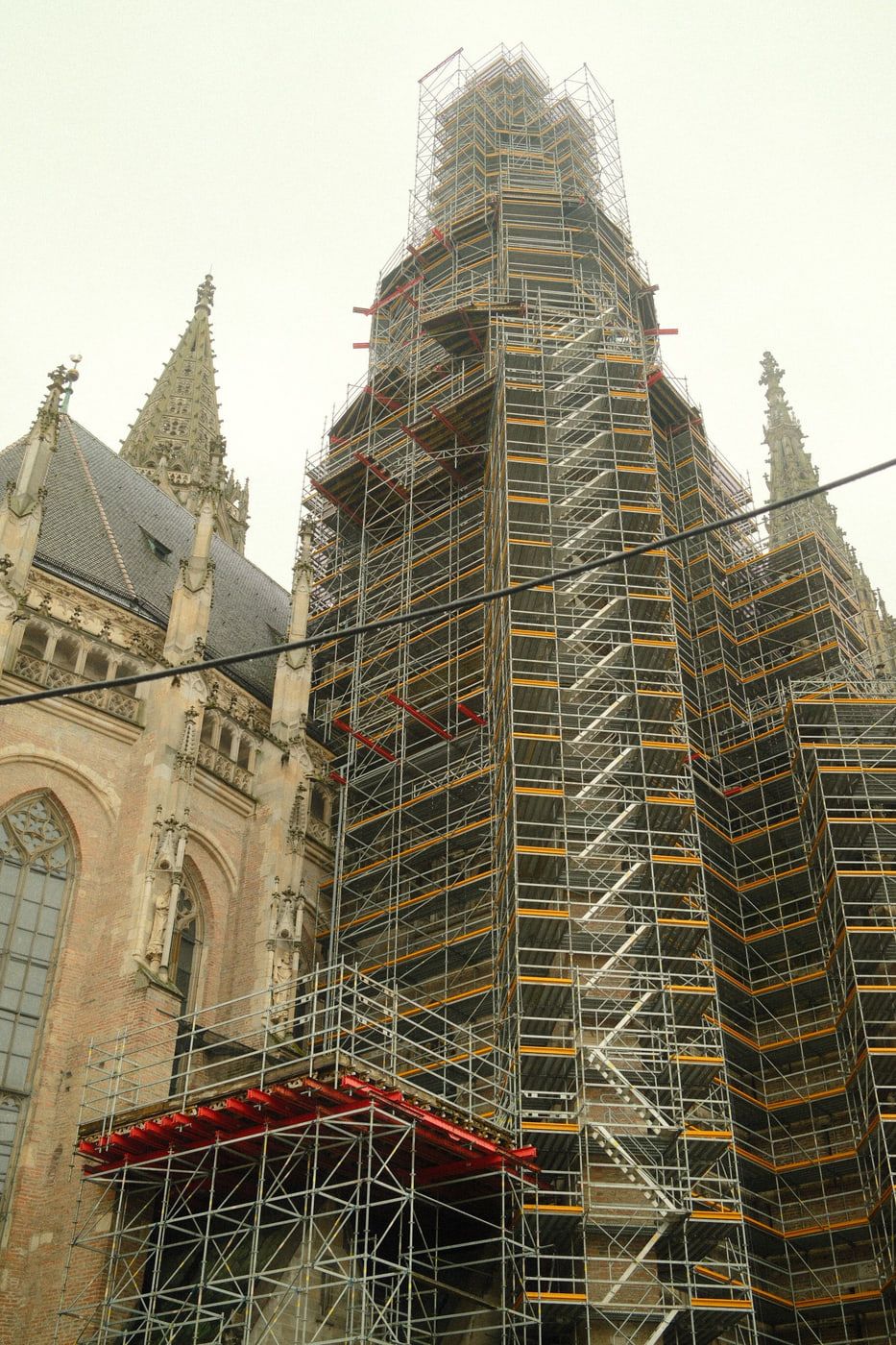 Vollständig eingerüsteter Kirchturm, an dem ein Treppenlauf im Zickzack bis nach oben führt